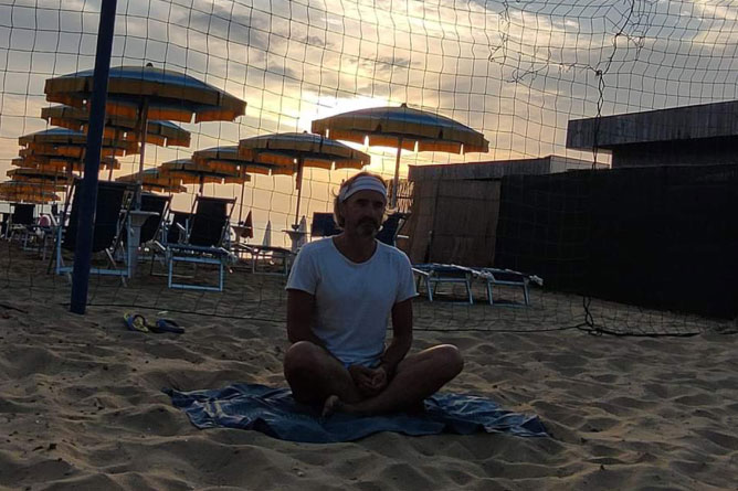 Uomo che fa yoga in spiaggia