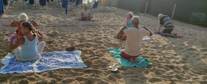 Gruppo di persone che fa yoga in spiaggia