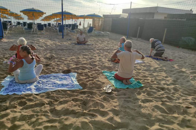 Gruppo di persone che fa yoga in spiaggia